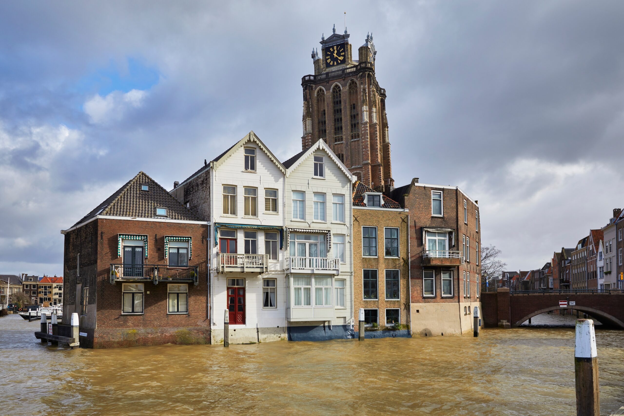 Overstroming in een Nederlandse stad met ondergelopen huizen en een kerk op de achtergrond.