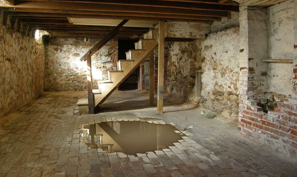 Kelder met een trap en een grote plas water op de grond