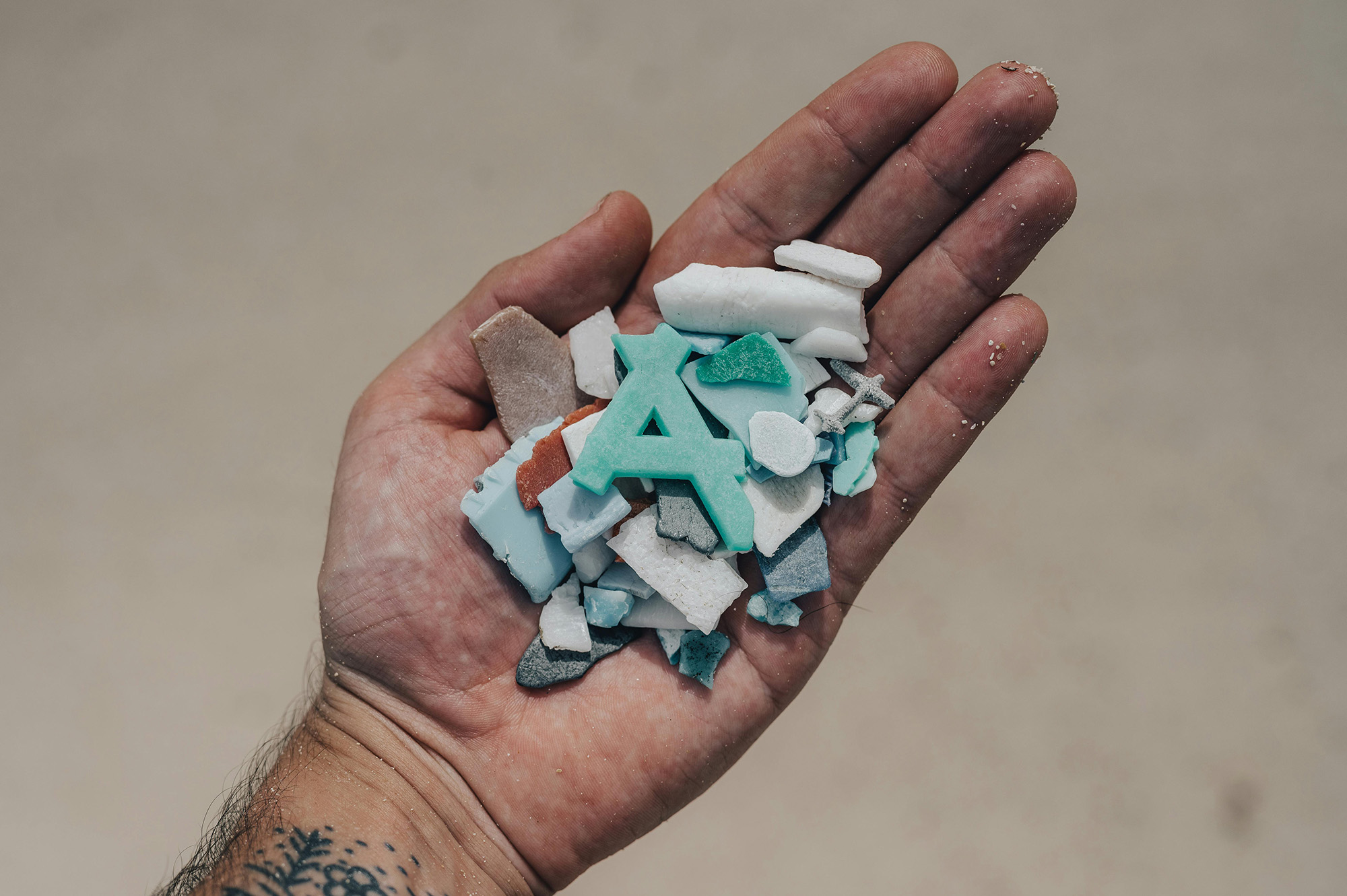 In een hand ligt klein plastic afval dat gevonden is in de natuur en daar dus niet hoort.